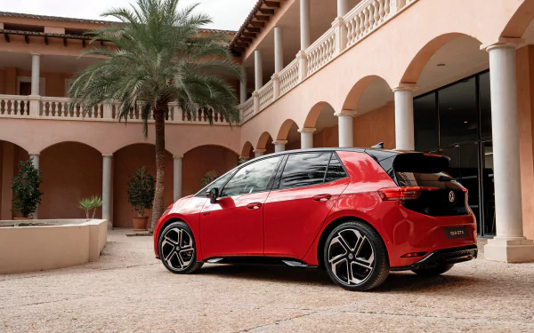 Red Volkswagen ID.3 GTX parked by a building, serving as a sleek HD desktop wallpaper of a modern electric vehicle.
