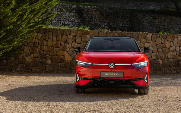 A stunning HD wallpaper featuring the Volkswagen ID.7 GTX Tourer, showcasing its sleek design and bold red color against a rustic stone backdrop.