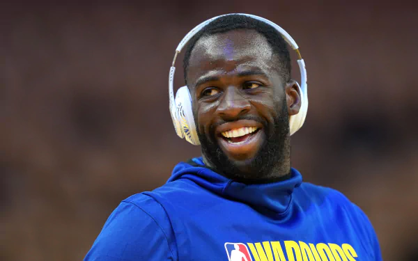 Draymond Green of the Golden State Warriors smiles while wearing headphones during warm-ups. This HD image captures the energy and spirit of NBA basketball.