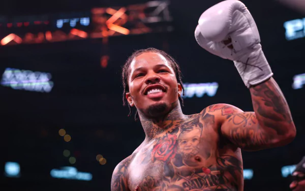 A boxer with tattoos triumphantly raises a gloved fist in the ring, exuding confidence and strength. The image serves as a HD desktop wallpaper and background.