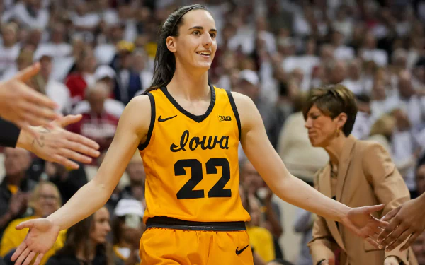 A smiling basketball player in an Iowa jersey with the number 22 receiving high-fives in a packed arena – HD desktop wallpaper and background.
