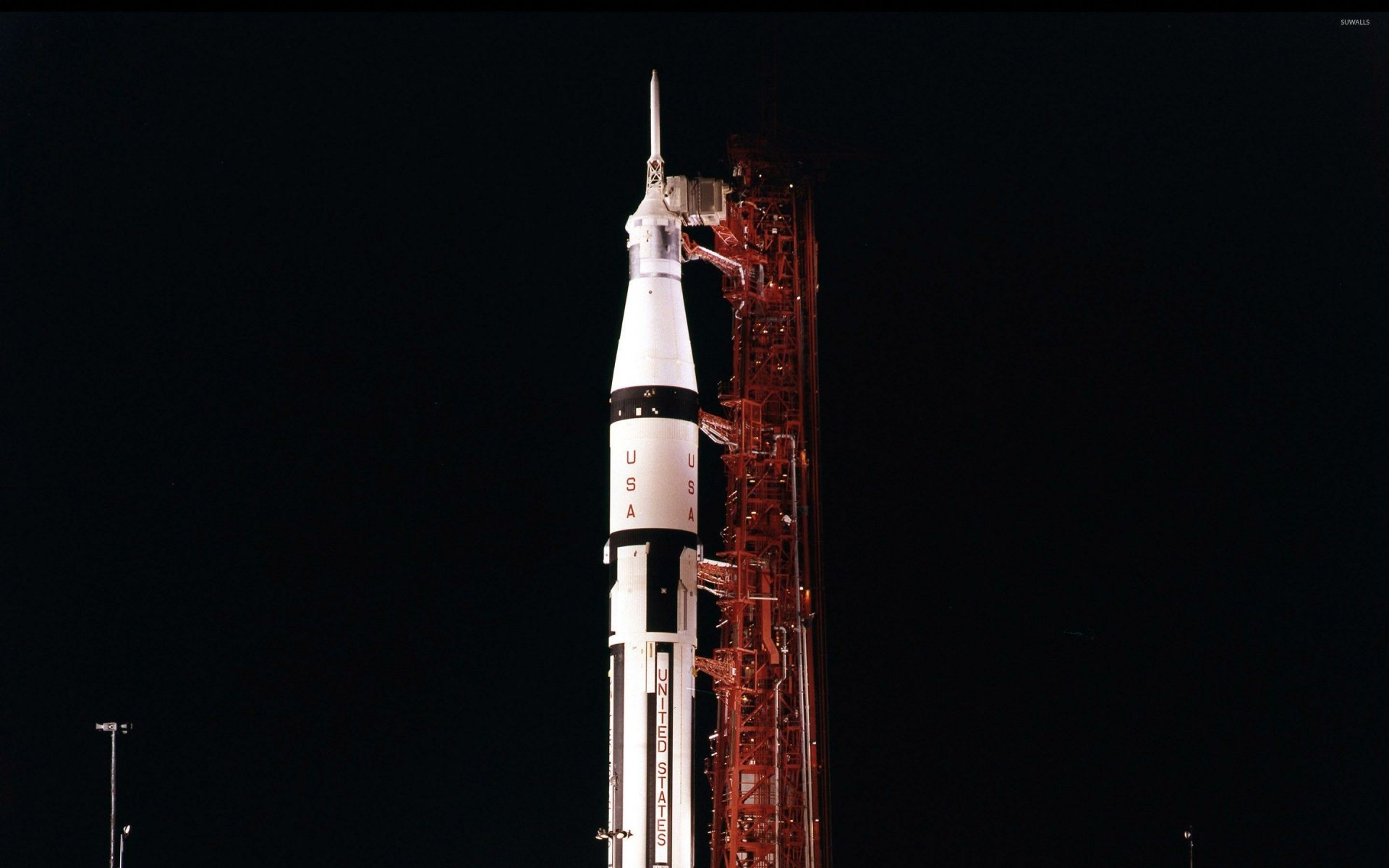 HD desktop wallpaper featuring the Saturn V rocket at night, poised for launch and illuminated against a dark sky.