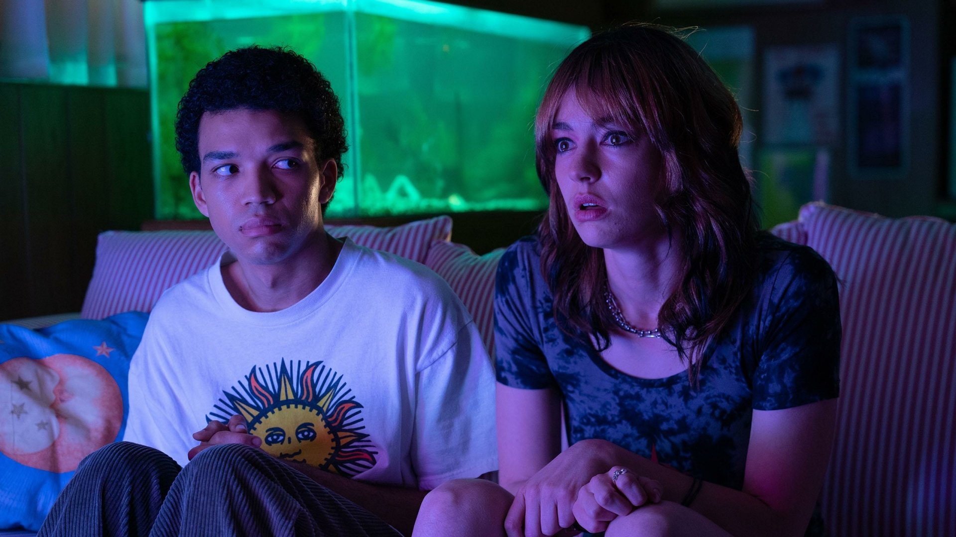 HD wallpaper of Justice Smith and Brigette Lundy-Paine in a scene from the movie I Saw the TV Glow, sitting together with a moody, neon-lit background.