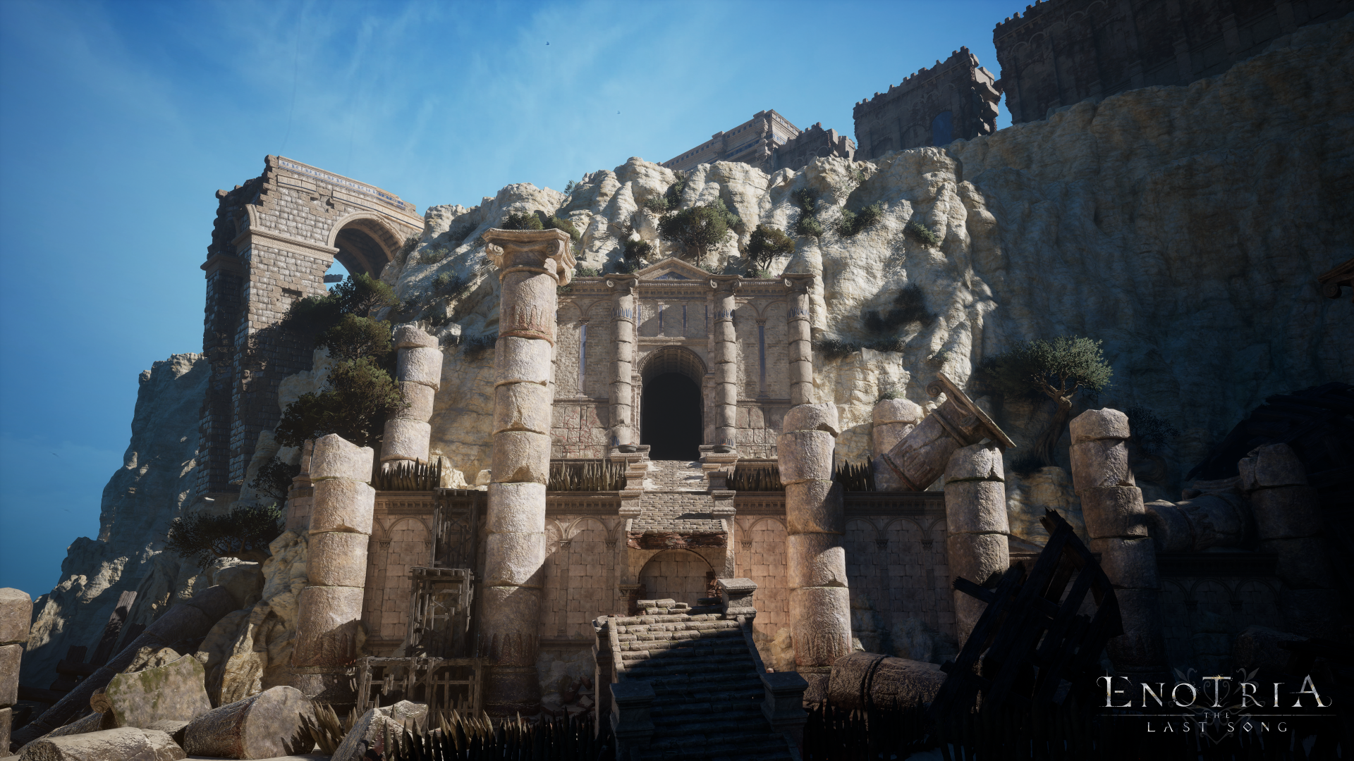 HD desktop wallpaper and background from the video game Enotria: The Last Song, featuring ancient stone ruins against a rugged mountainside under a clear blue sky.