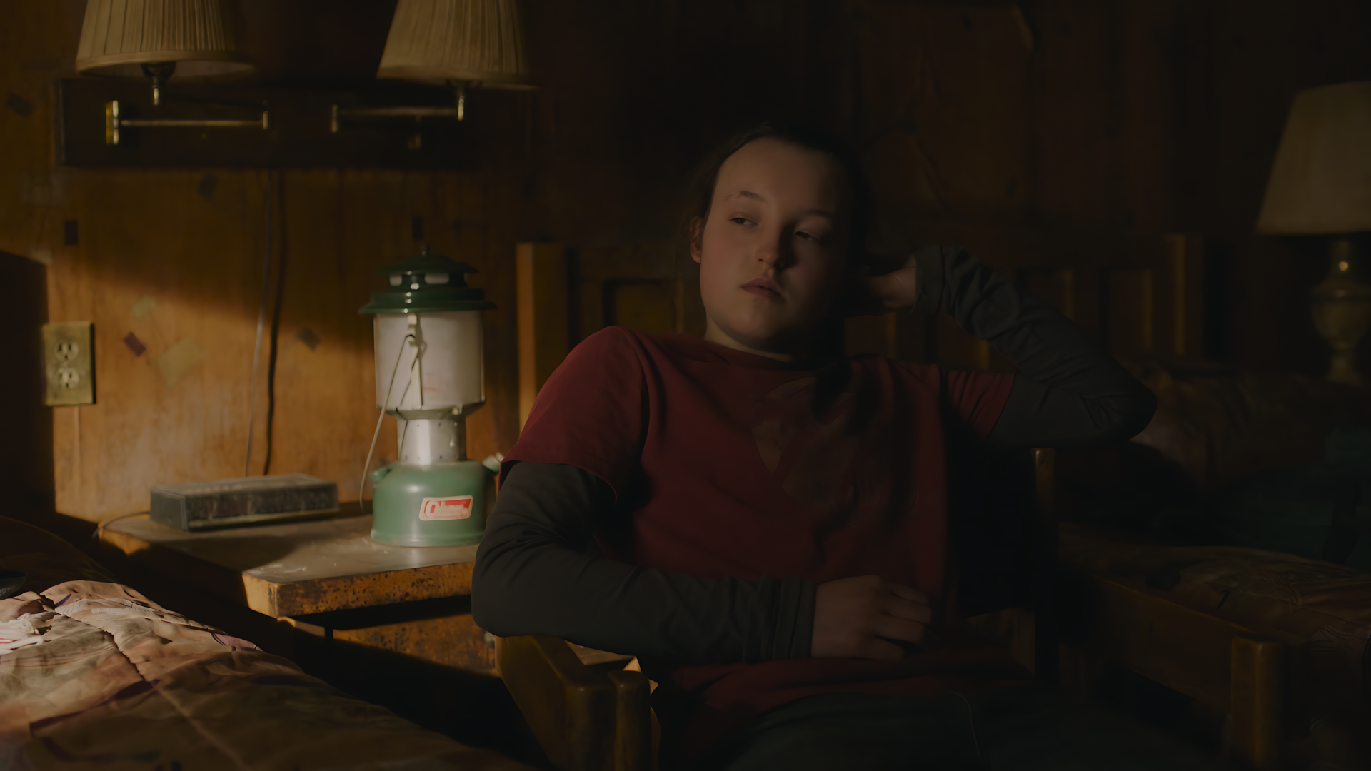 8K Ultra HD PC desktop wallpaper featuring a dimly lit scene from The Last Of Us, showing a character sitting in a rustic cabin interior.