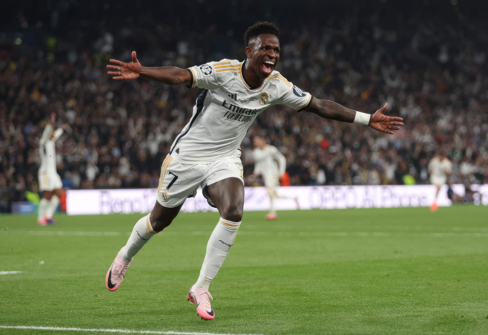Vinícius Júnior celebrates a goal in a Real Madrid C.F. soccer match, with a stadium crowd in the background. This HD image serves as a dynamic desktop wallpaper.