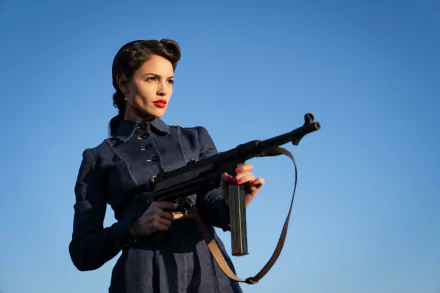 A woman in a vintage military-style outfit holding a submachine gun against a clear blue sky, conveying a theme related to the movie The Ministry of Ungentlemanly Warfare. Used as a high-definition desktop wallpaper and background.