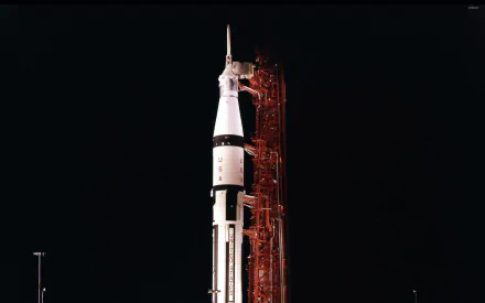 HD desktop wallpaper featuring the Saturn V rocket at night, poised for launch and illuminated against a dark sky.
