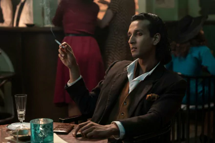 HD desktop wallpaper from Interview with the Vampire featuring a character in a smokey bar scene, holding a cigarette and sitting at a table.