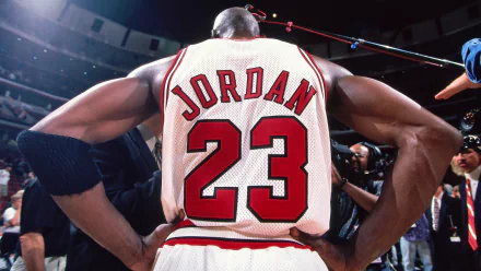 HD desktop wallpaper featuring basketball legend Michael Jordan, wearing Chicago Bulls jersey number 23. The image captures his back as he stands surrounded by cameras. Tags: Sports, NBA, Chicago Bulls, basketball.
