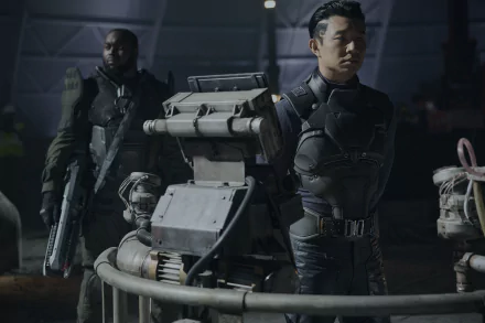 HD desktop wallpaper featuring a scene from the movie Atlas (2024), showing two individuals in futuristic attire standing behind a robotic machine in a dimly lit environment.