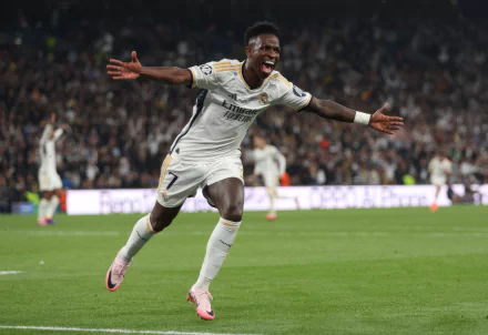 Vinícius Júnior celebrates a goal in a Real Madrid C.F. soccer match, with a stadium crowd in the background. This HD image serves as a dynamic desktop wallpaper.