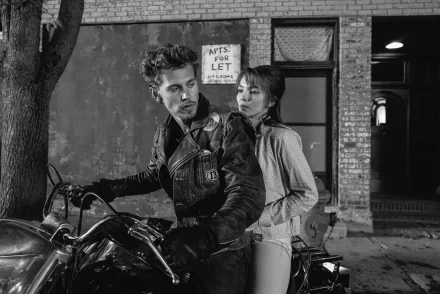 Black and white HD desktop wallpaper featuring a scene from the movie The Bikeriders with Austin Butler and Jodie Comer, showing them seated on a motorcycle in a gritty, urban setting.