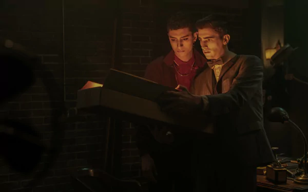 HD desktop wallpaper from the TV show Dead Boy Detectives featuring two young male characters examining a document in a dimly lit room.