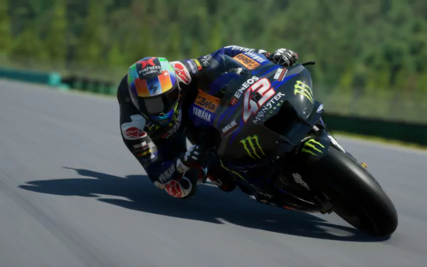 HD desktop wallpaper from the video game MotoGP 24, featuring a motorcycle racer leaning sharply into a turn on a race track.
