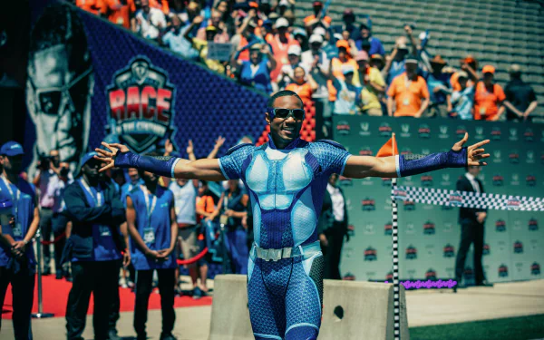 HD desktop wallpaper of A-Train from The Boys TV show, posing at a public event with a vibrant crowd in the background.