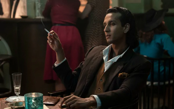 HD desktop wallpaper from Interview with the Vampire featuring a character in a smokey bar scene, holding a cigarette and sitting at a table.