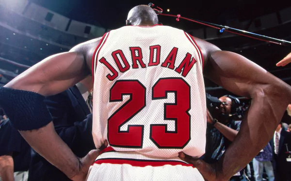 HD desktop wallpaper featuring basketball legend Michael Jordan, wearing Chicago Bulls jersey number 23. The image captures his back as he stands surrounded by cameras. Tags: Sports, NBA, Chicago Bulls, basketball.
