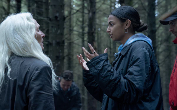 HD wallpaper featuring a scene from the 2024 movie The Watchers. Characters engage in an intense conversation in a dimly lit forest.
