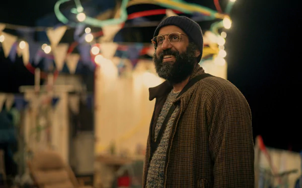 HD wallpaper featuring a scene from the TV show Sweet Tooth, showcasing a bearded man wearing a hat and glasses at a colorful, festive outdoor setting with lights and bunting in the background.