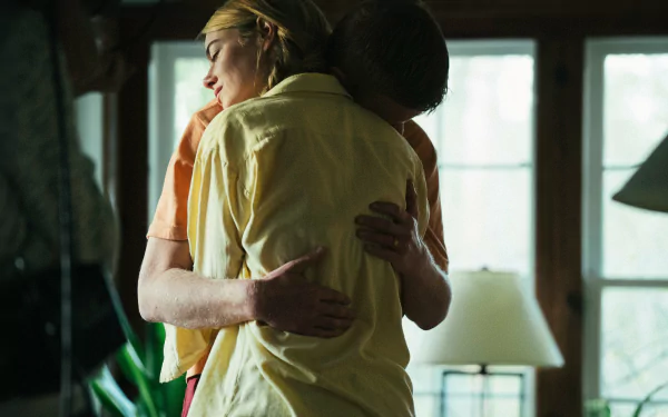 HD desktop wallpaper titled Movie, Kinds of Kindness, features two people embracing tenderly in a sunlit room.