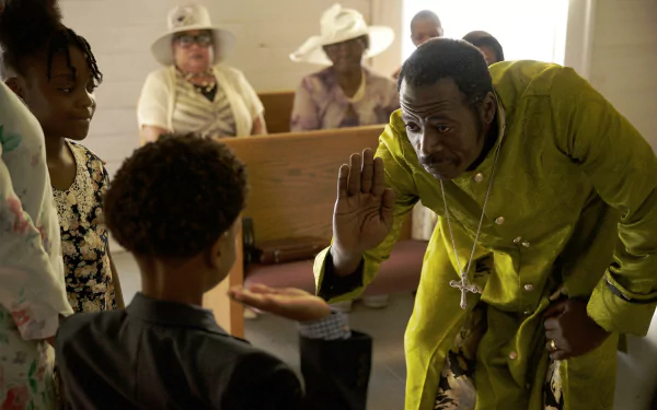 A scene from the movie Sound of Hope: The Story of Possum Trot, featuring a man in a green outfit interacting with a young boy in a church setting. The wallpaper is in HD quality.
