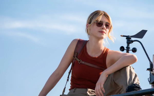 HD desktop wallpaper featuring Daisy Edgar-Jones from the movie Twisters, sitting casually with weather equipment against a clear sky background.