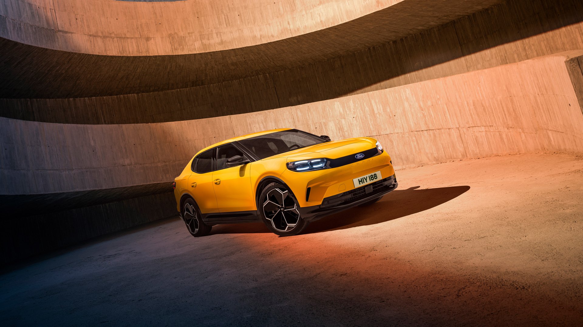 A striking yellow Ford Capri parked in a modern architectural setting, showcasing its sleek design. This HD desktop wallpaper captures the car's dynamic presence and style.