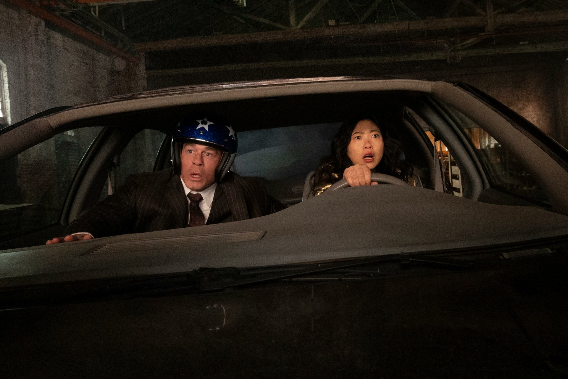 Two characters in a car with expressions of surprise and urgency, set in a dramatic scene from the movie Jackpot!. High-definition desktop wallpaper capturing their tense moment.