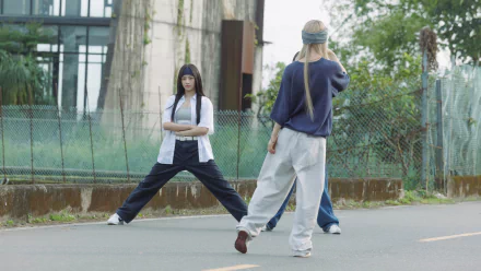 High-definition desktop wallpaper featuring NewJeans performing a dynamic dance routine on an urban street, showcasing movement and style against a modern backdrop.