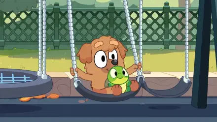A charming HD desktop wallpaper from the TV show Bluey, featuring a playful puppy swinging with a green toy, set against a vibrant playground backdrop.
