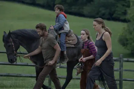 A scene from the TV show Teacup (2024) featuring Scott Speedman and Yvonne Strahovski, showing a family walking a horse in a lush, green landscape.