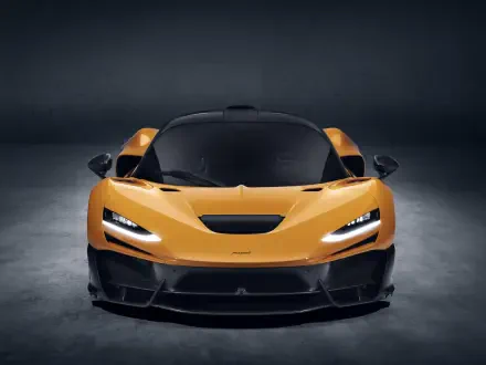A stunning McLaren W1 in vibrant orange, showcased in a sleek studio setting, serves as an impressive 8K Ultra HD desktop wallpaper and background.
