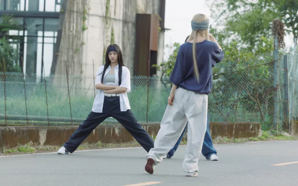 High-definition desktop wallpaper featuring NewJeans performing a dynamic dance routine on an urban street, showcasing movement and style against a modern backdrop.