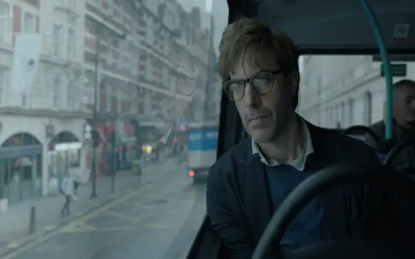 A 4K Ultra HD wallpaper featuring a scene from the TV show Disclaimer (2024), showcasing Sacha Baron Cohen looking pensively from a bus amid a rainy city backdrop.