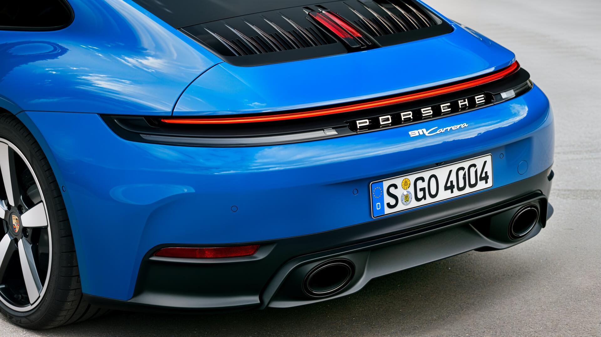 A striking blue Porsche 911 Carrera features sleek lines and a sporty rear design, making it a captivating 4K Ultra HD desktop wallpaper and background.