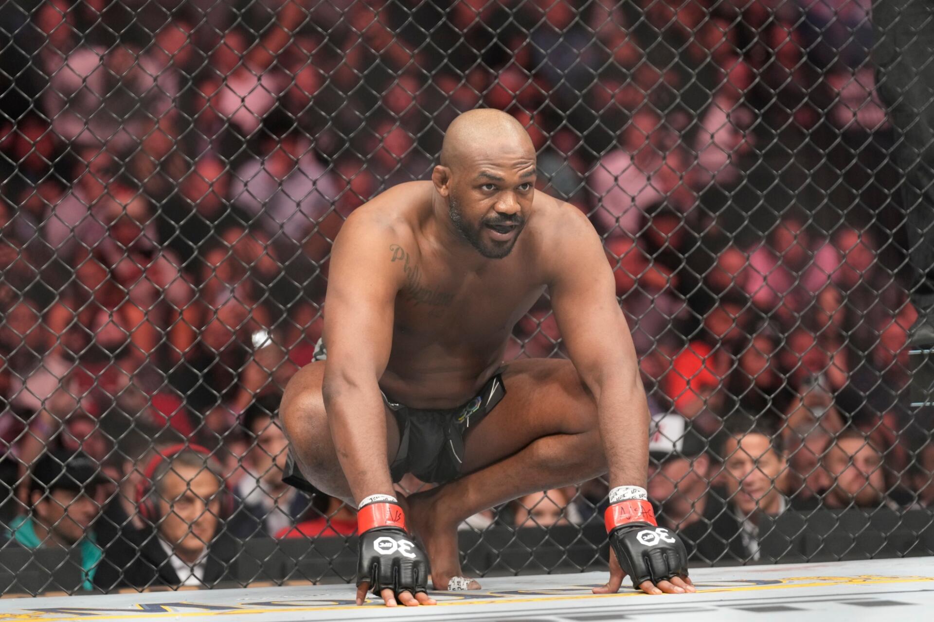 Jon Jones crouches in an intense moment inside the octagon during a UFC fight, showcasing the raw energy of MMA. This dynamic HD image serves as a striking desktop wallpaper.