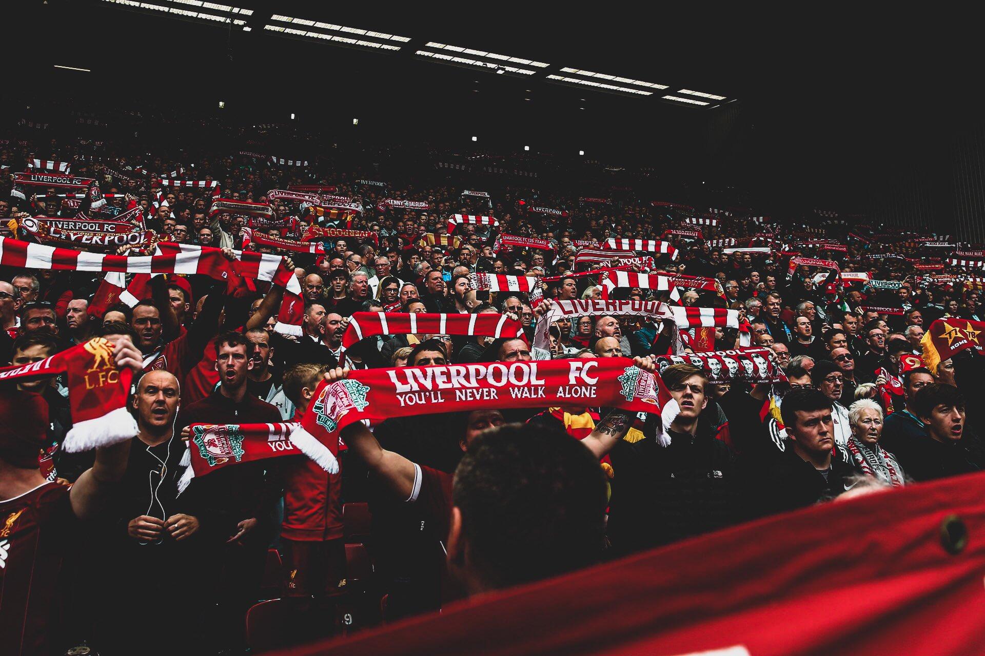 A vibrant crowd of Liverpool F.C. fans waves red and white scarves, showcasing their passion for soccer in this striking HD desktop wallpaper.