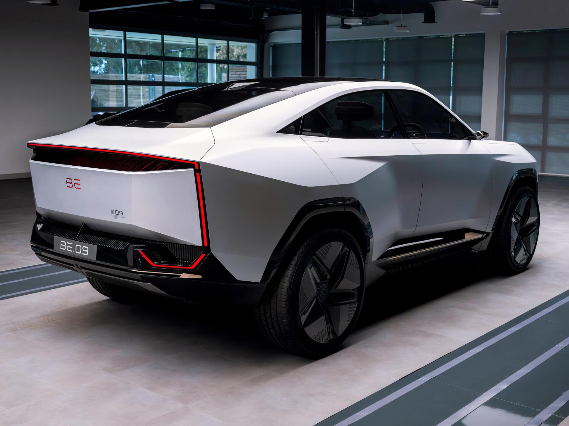 HD desktop wallpaper featuring the sleek, futuristic Mahindra BE 09 car in a modern indoor setting.