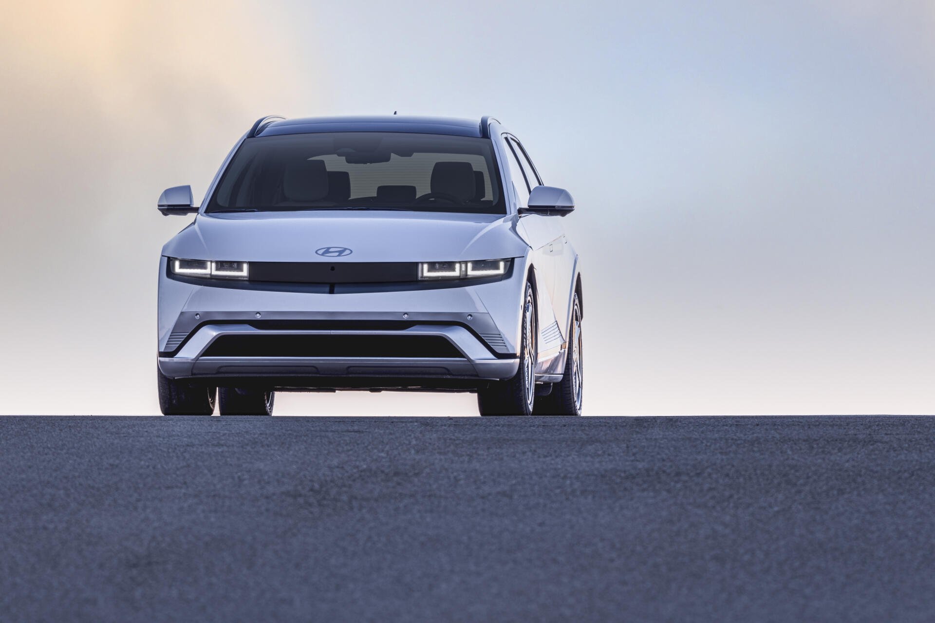 A sleek Hyundai IONIQ 5 showcases its modern design with sharp lines and distinctive headlights against a soft sky, captured in stunning 4K Ultra HD.