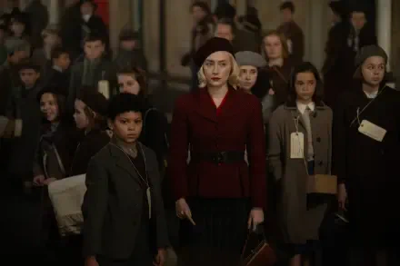 A scene from the movie Blitz (2024), featuring Saoirse Ronan in a striking red coat, leads a group of children in a historical setting, highlighting themes of resilience and unity.