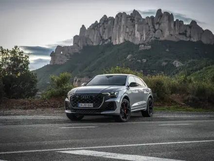 An Audi RS Q8 is showcased on a scenic road, framed by dramatic mountains. This stunning image serves as a 4K Ultra HD desktop wallpaper and background.