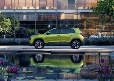 A vibrant green Škoda Kylaq parked beside a serene pond, surrounded by lush greenery, showcased in a stunning 4K Ultra HD desktop wallpaper.