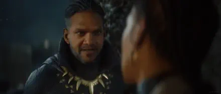 A dramatic scene from the video game MARVEL 1943: Rise of Hydra, featuring a character in a dark cloak adorned with an iconic necklace, set against an atmospheric background.