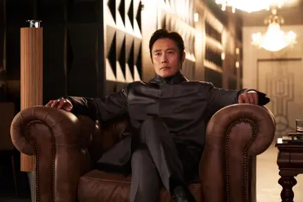 A high-definition desktop wallpaper featuring Lee Byung-hun from the TV show Squid Game, seated confidently in a luxurious chair, set against an elegant background.
