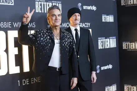 Robbie Williams poses at the premiere of Better Man (2024), showcasing his signature style against a backdrop featuring the movie's branding. 8K Ultra HD wallpaper.