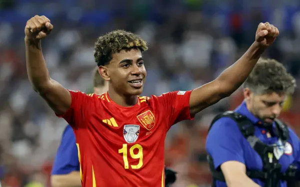 Lamine Yamal celebrates on the field, wearing the Spain National Football Team jersey number 19, capturing the spirit of soccer in this vibrant HD desktop wallpaper.