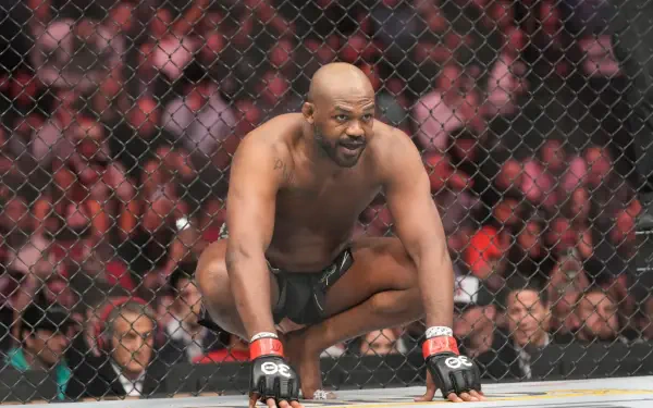 Jon Jones crouches in an intense moment inside the octagon during a UFC fight, showcasing the raw energy of MMA. This dynamic HD image serves as a striking desktop wallpaper.