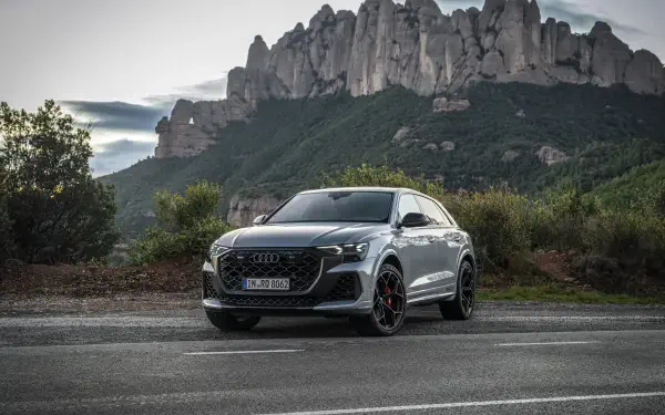 An Audi RS Q8 is showcased on a scenic road, framed by dramatic mountains. This stunning image serves as a 4K Ultra HD desktop wallpaper and background.