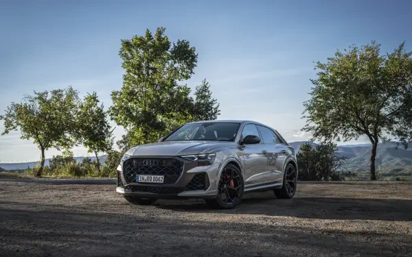 A stunning Audi RS Q8 parked against a scenic backdrop of trees, showcasing its sleek design and sporty features in vibrant 4K Ultra HD resolution.